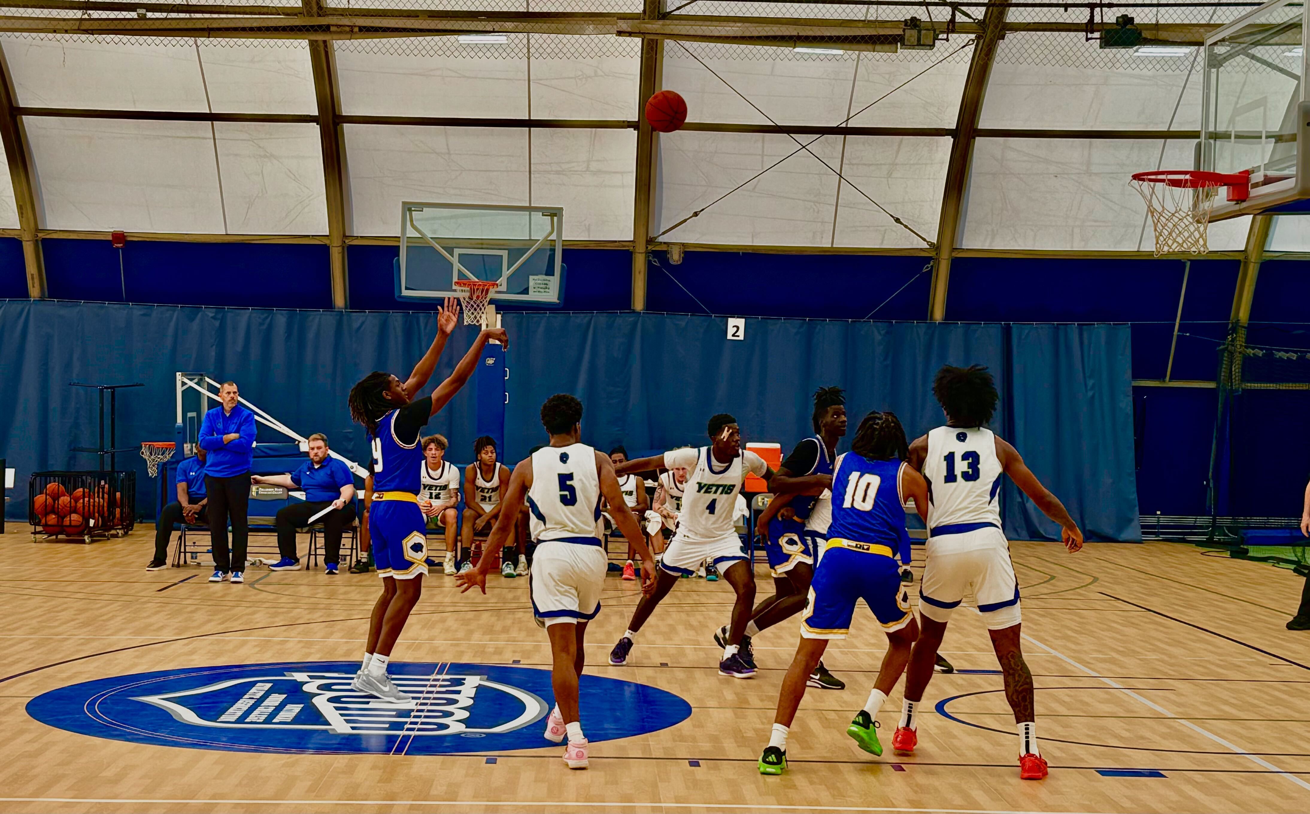 Photo of basketball player leaping into the air to shoot a hoop with other players looking on.