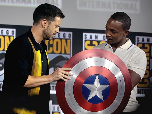 Anthony Mackie holding the Captain America shield with Sebastian Stan at San Diego Comic Con 2019.