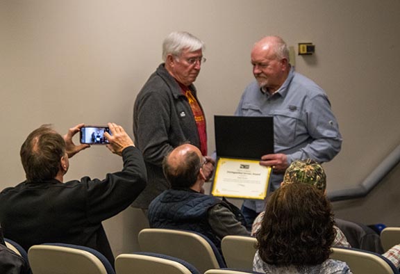 An observer captures a photo on his phone of Brad Cottrell receiving an award for his work with the Southern Appalachian Nature Photographers association. | Sophie Perrins